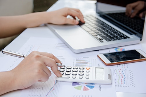 close up woman using calculator and laptop on paper graph data w