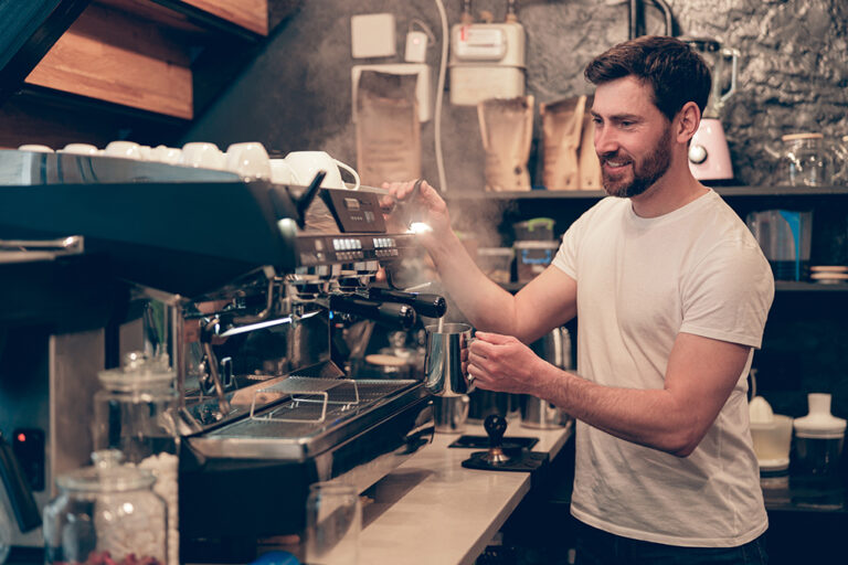 Caucasian happy male bartender making coffee at professional machine. Work in cafeteria